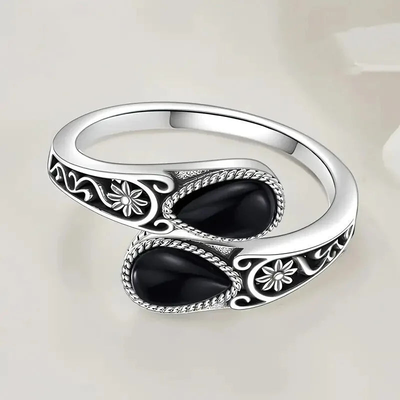 Silver-tone ring with two dark oval stones and engraved flower details