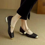 Black satin ballet flats with Mary Jane strap, bow detail, and low jeweled block heel.