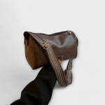 Brown retro crossbody bag with woven adjustable strap and top zip closure.