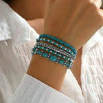 Turquoise beaded bracelets with silver filigree and oval charms worn on wrist