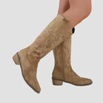 Tan suede cowboy western boots on foot, pull-on, low heel with stitched star motif
