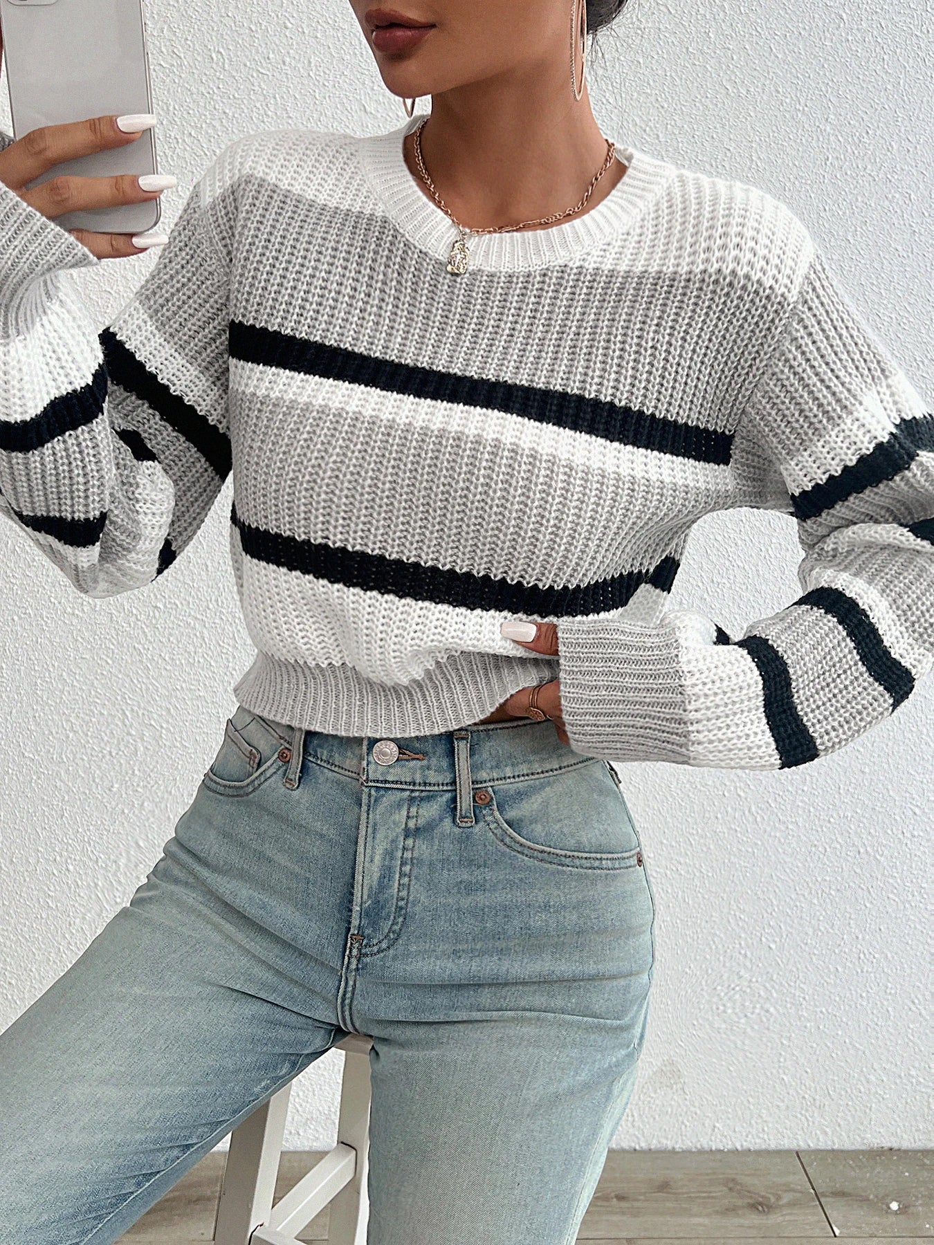 Oversized knit sweater in off-white with black horizontal stripe across chest and sleeves