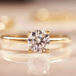 Gold solitaire ring with large round clear gemstone and four small prongs