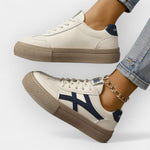 Platform retro sneakers in white with navy stripes, tan platform sole, floral side emblem.