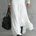 Long white dress with fitted bodice, sheer sleeves, and layered ankle-length hem