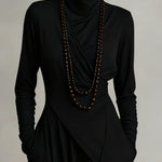 Close-up of black asymmetric draped long dress with cowl neck and long sleeves