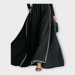 Black maxi skirt with draped pleats and contrast white piping along hem and trim
