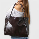 Dark brown leather-look tote bag on model, smooth finish and wide opening
