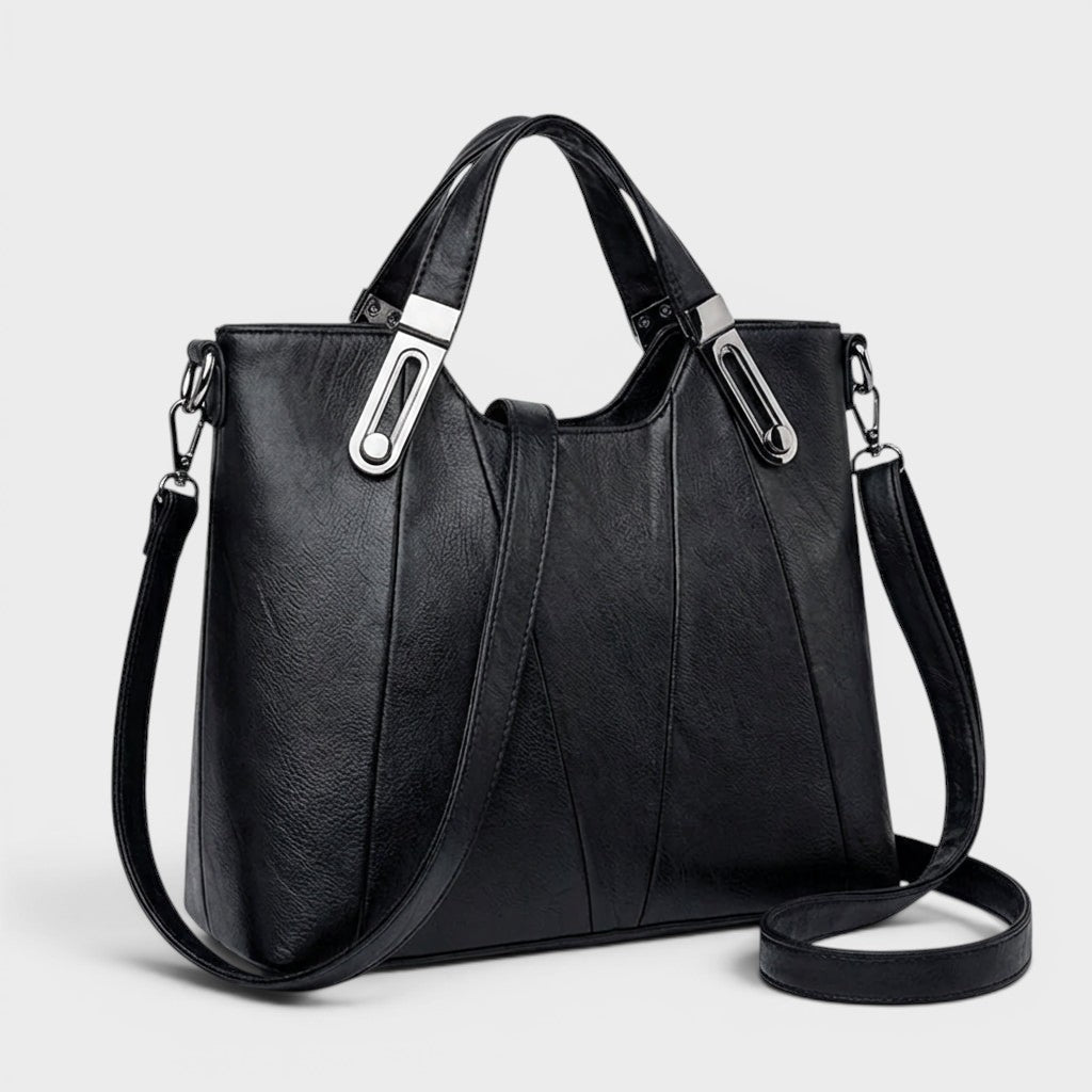 Black leather handbag with top handles, metal buckles, and long crossbody strap