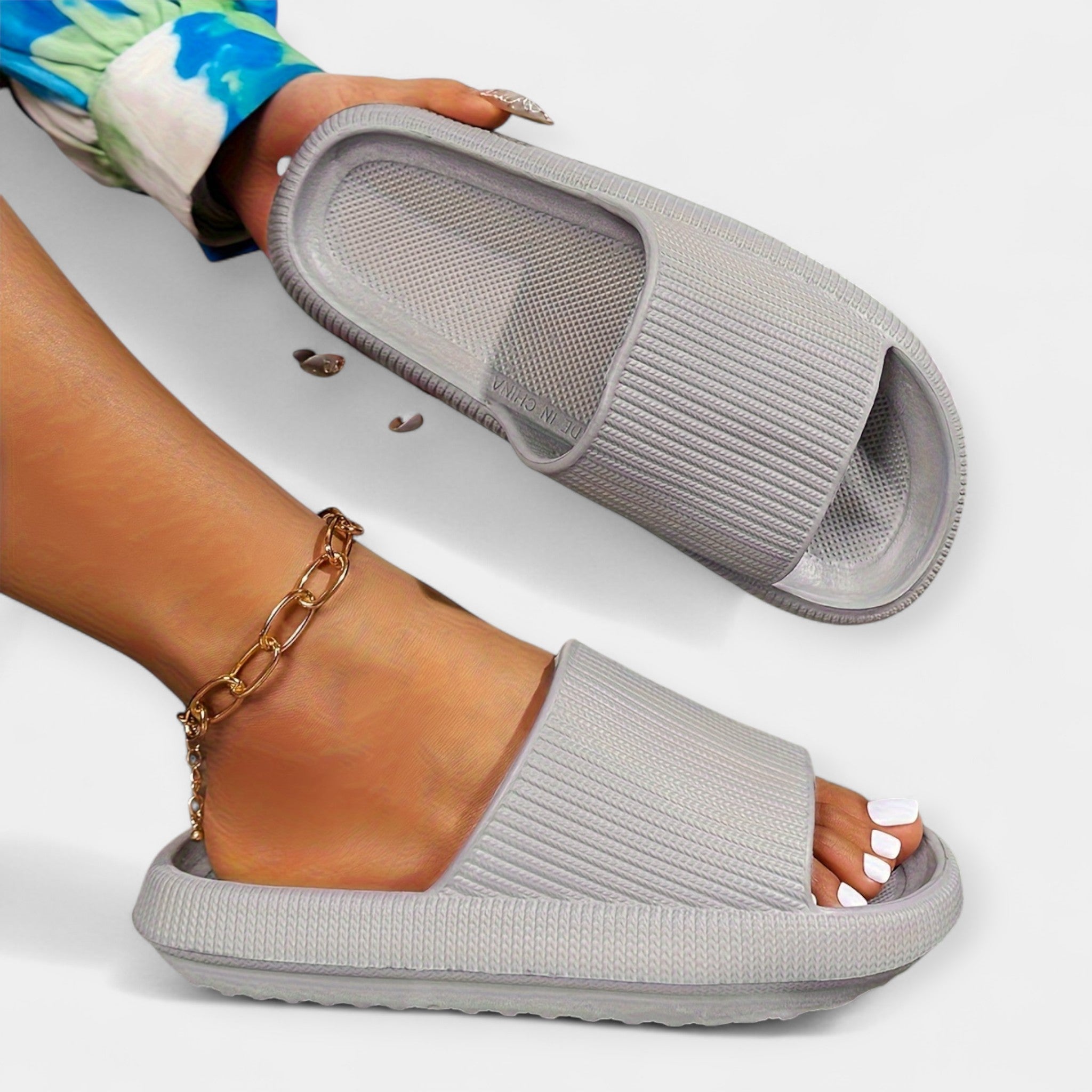 Gray slide sandals with wide strap, open toe, and cushioned textured sole