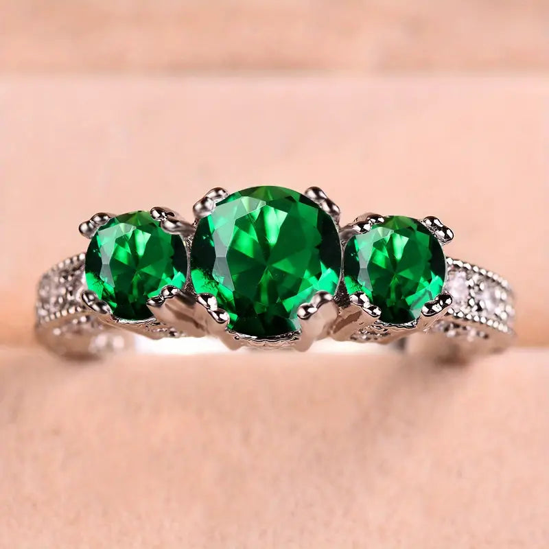 Emerald-stone ring featuring three large green gems on a silver band