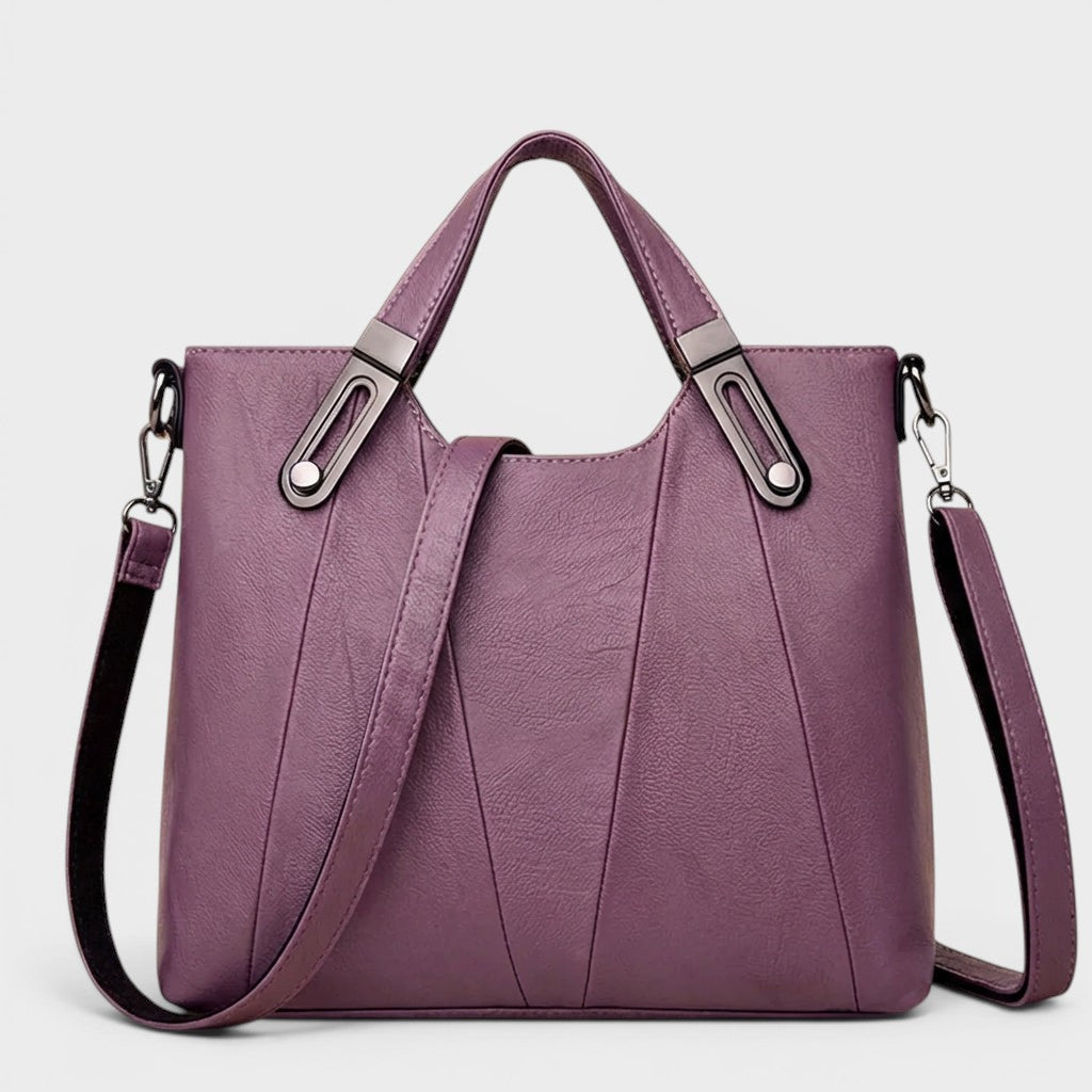 Purple leather handbag with top handles, metal buckles, and detachable side strap