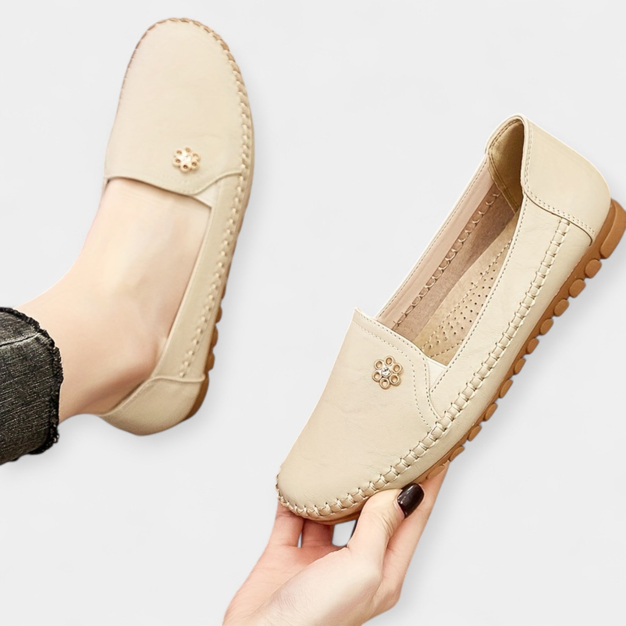 Beige slip-on loafers with floral emblem, stitched apron toe, and textured sole