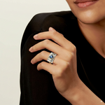 Silver statement ring with oval blue crystal in gold bezel, worn on finger