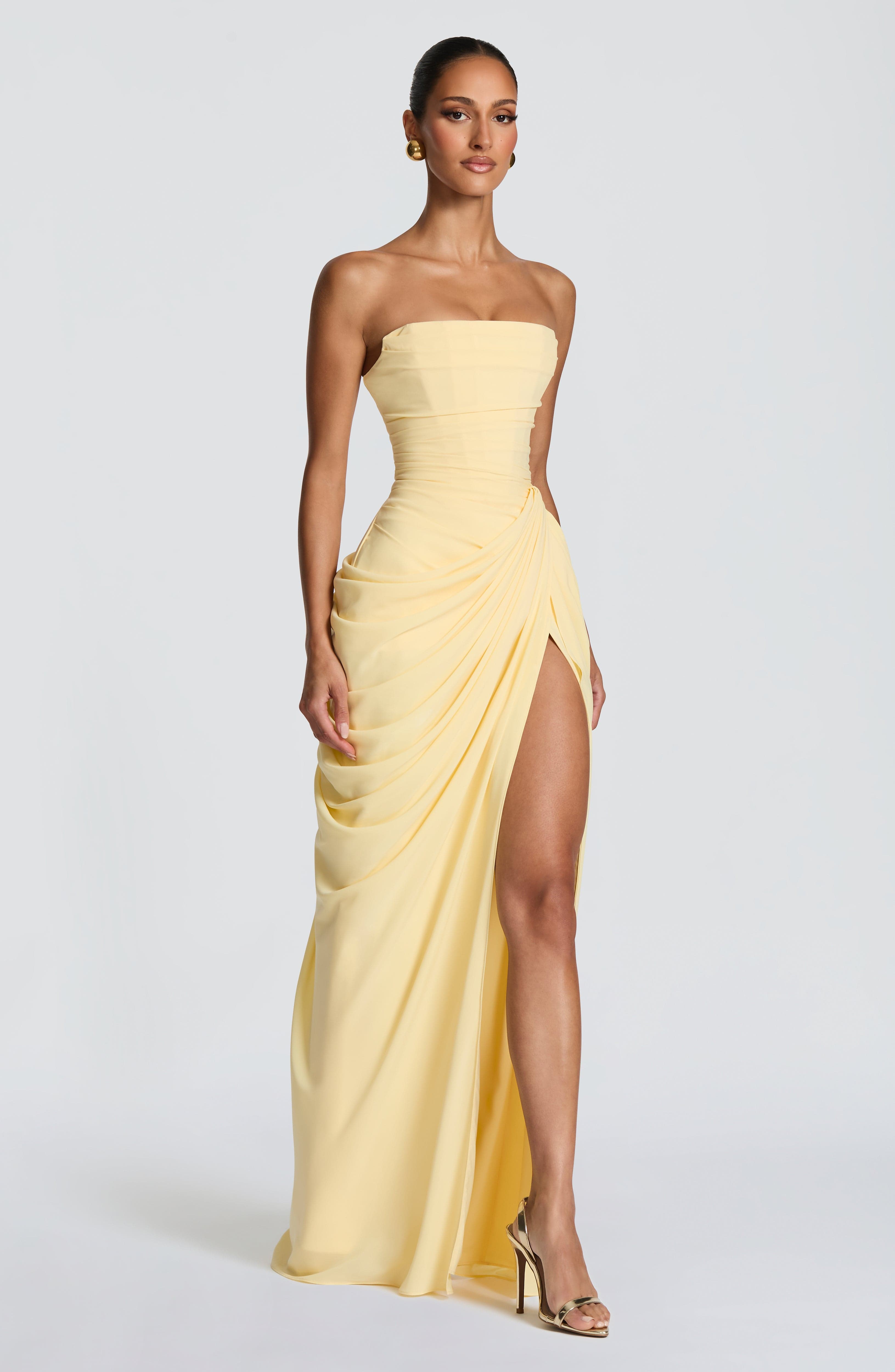 Pale yellow strapless corset maxi dress with draped skirt and high front slit