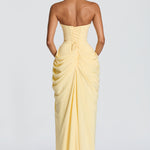 Back view of pale yellow strapless corset maxi dress with gathered drape and slit