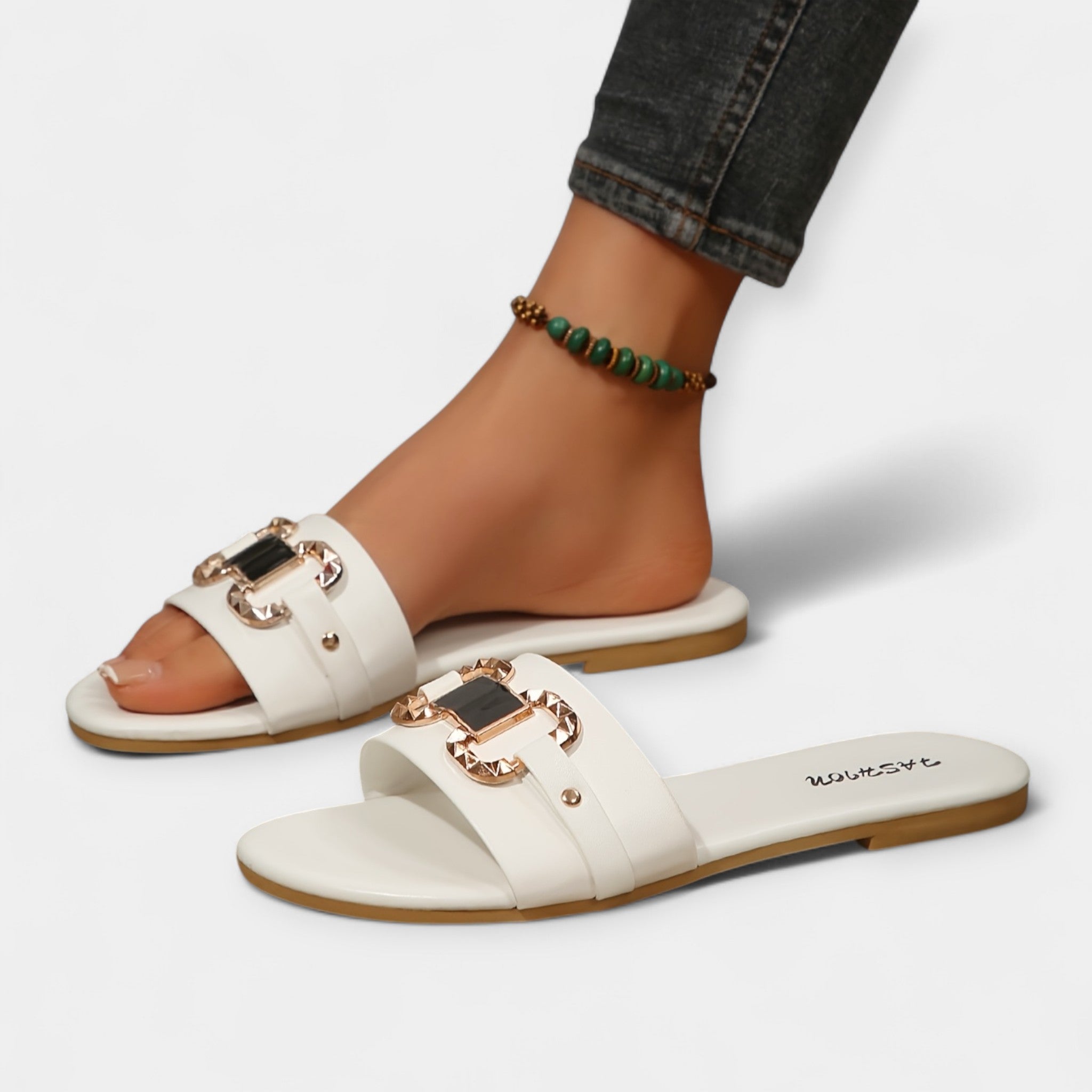 White slide sandals with round toe, double straps, and gold-tone buckles