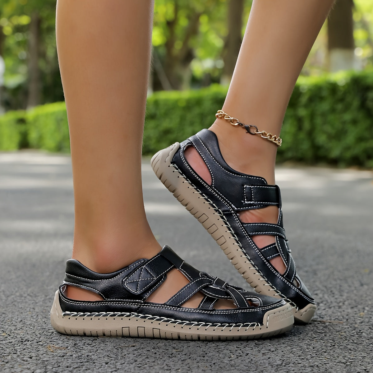 Lightweight summer sandals in dark navy/black on feet with ankle chain detail