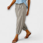 Light gray harem pants with side pockets and button-tab cuffs, relaxed loose fit