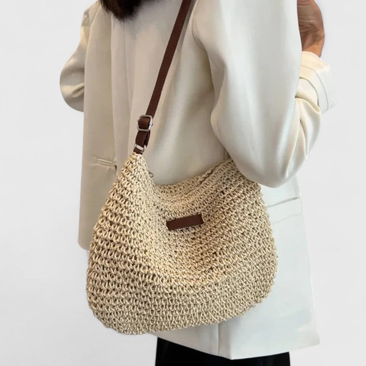 Beige woven crescent shoulder bag with brown leather strap and front patch