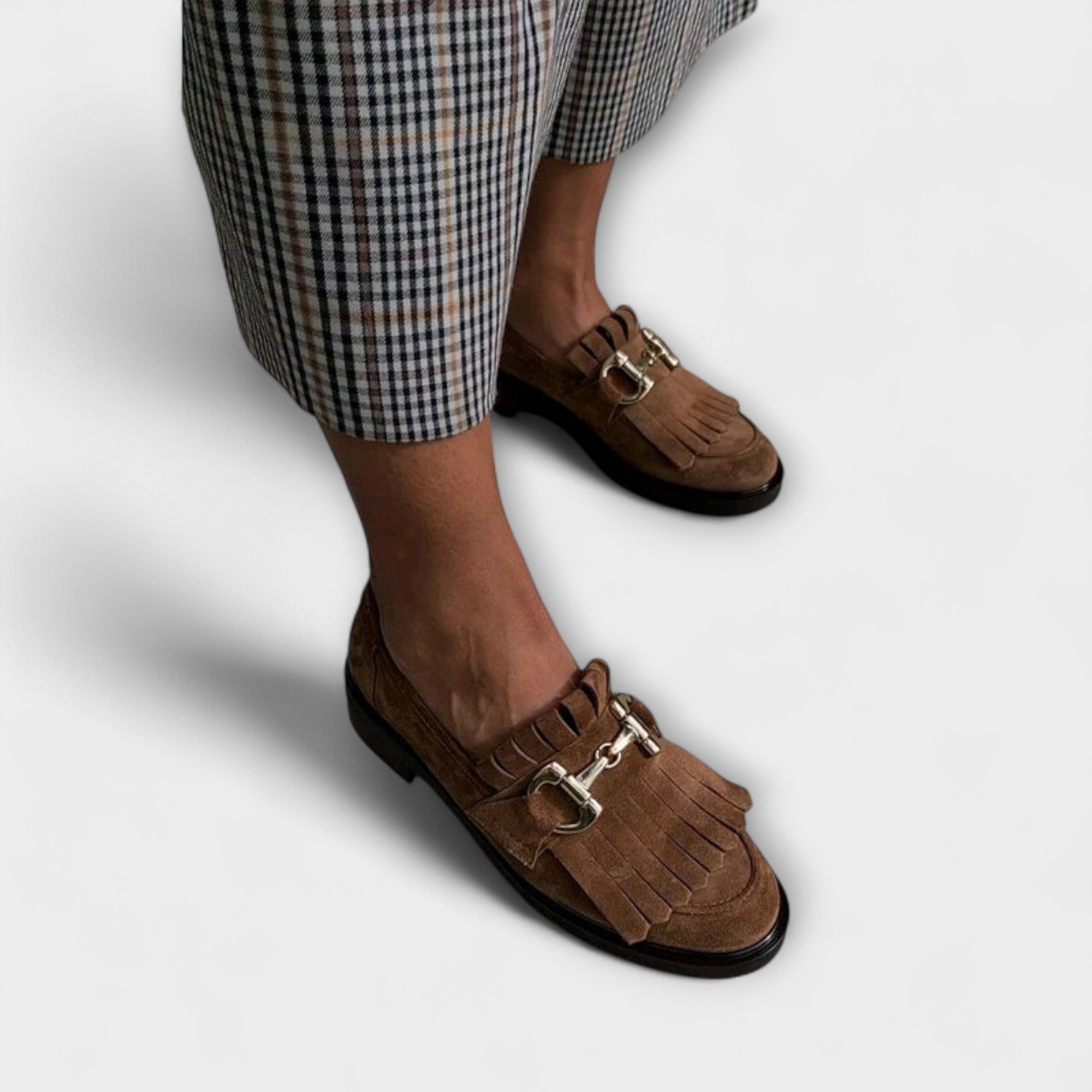 Brown suede moccasin shoes with round toe, fringe detail, metal buckle strap