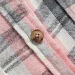 Plaid shirt fabric detail with brown button and white contrast trim