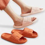 Light pink and orange slide sandals on feet, padded straps and open-toe slides