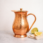 Copper jug with hammered texture, domed lid, and arched side handle