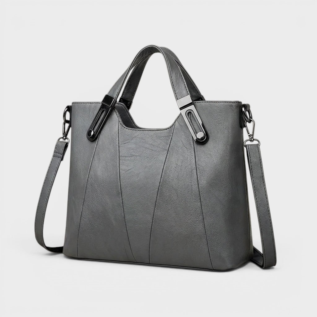 Gray leather handbag with structured sides, top handles, and shoulder strap