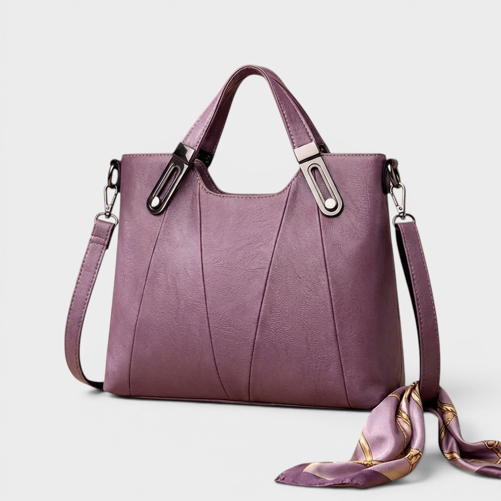 Purple leather handbag with top handles, front seam panel, and side strap