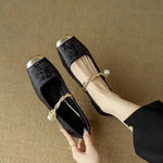 Black ballet flats with Mary Jane strap and bow, showing the low block heel.