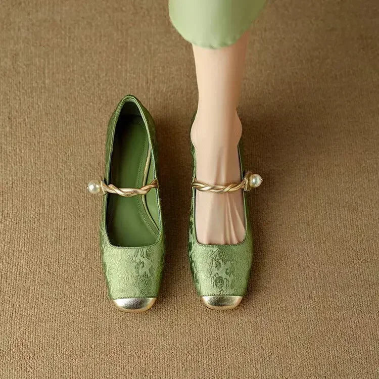 Pair of green ballet flats with Mary Jane strap, bow, and low heel block detail.