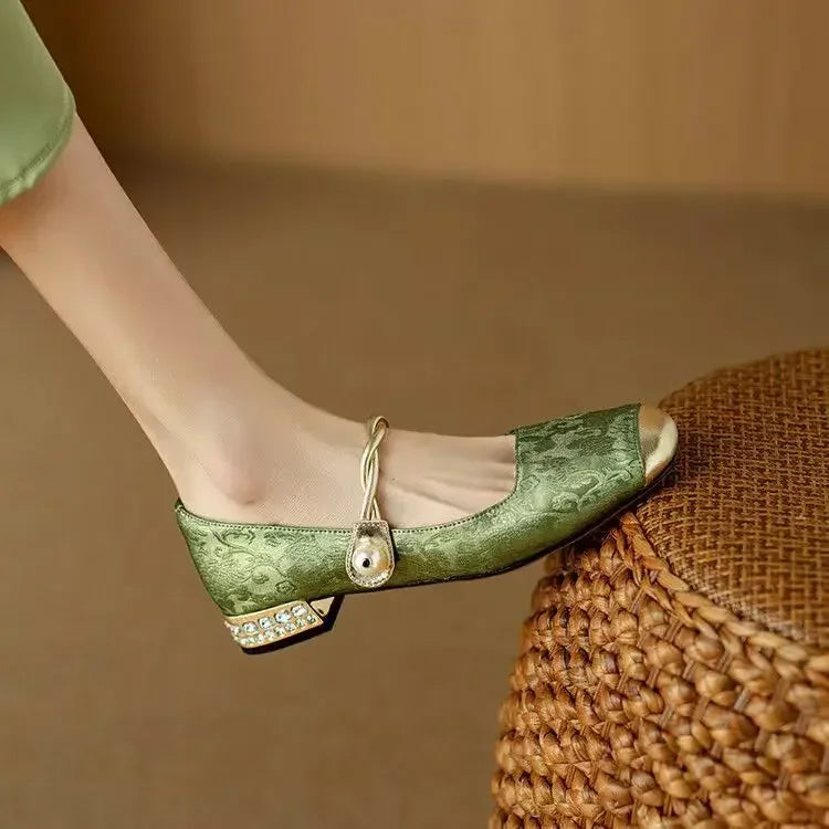 Green closed-toe ballet flats with Mary Jane strap, bow, and small jeweled heel trim.