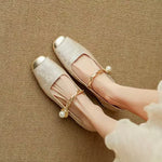 Beige/gold ballet flats with Mary Jane strap, bow detail, and low block heel.