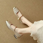 Gold-tone ballet flats with Mary Jane strap, bow, and low block heel detail.