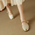Gold-tone ballet flats with Mary Jane strap, bow, and low heel on model’s feet.