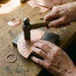 Copper hoop earring with hammered half-moon disc being assembled on a workbench