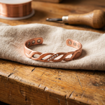 Copper bracelet with swirling cutout design and small rhinestones, adjustable fit