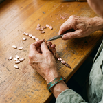 Copper bracelet links and oval plates being assembled on a workbench with tools
