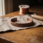 Copper cuff bracelet with engraved floral pattern and two holes at each end