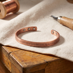 Copper bracelet with oval cutouts and engraved floral pattern along the band
