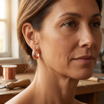 Copper hoop earrings with starburst texture, worn on ear