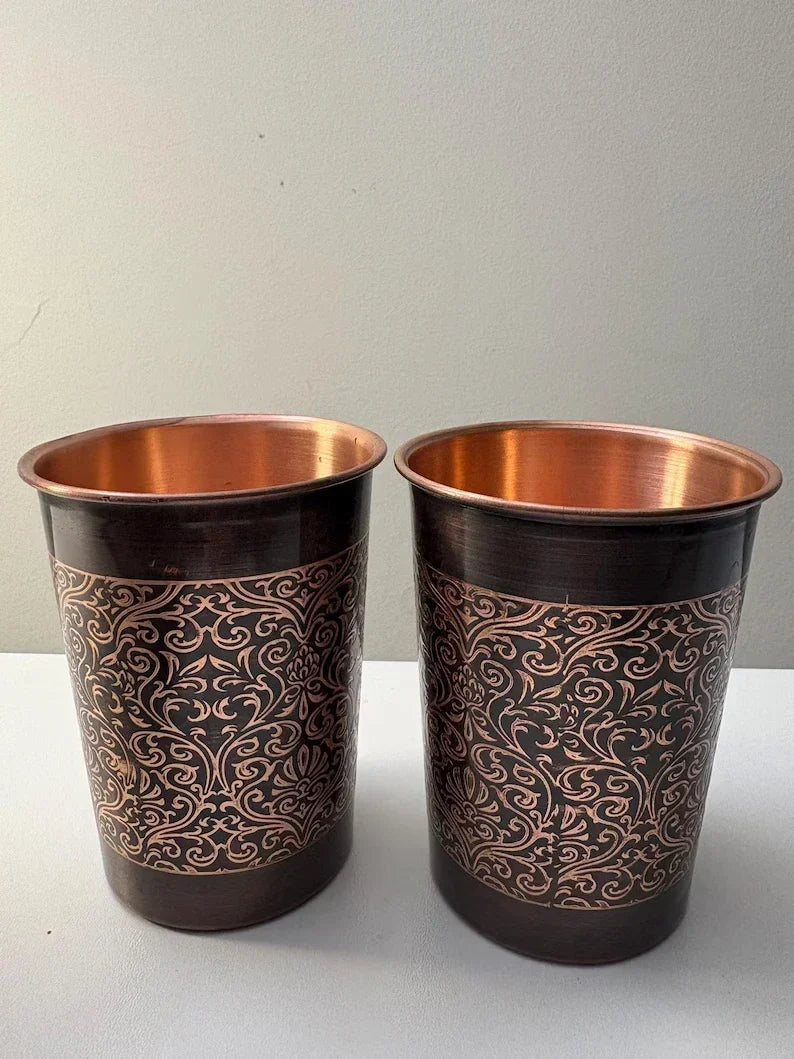 Two copper mugs with gold floral scroll pattern and copper interiors, dark bronze finish