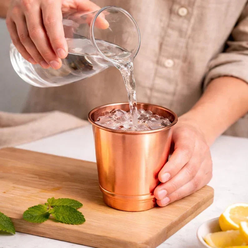 Copper 350 ml cup being filled with water and ice, with mint and lemon nearby