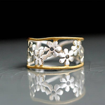 Gold-tone floral cutout ring with white petal stones in a wide band