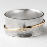 Gold-tone ring with rounded silver band and small clear gemstone centerpiece