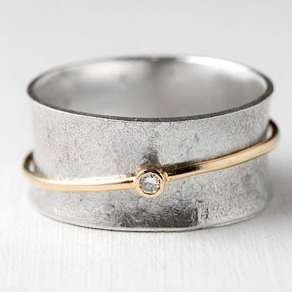 Gold-tone ring with rounded silver band and small clear gemstone centerpiece