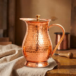 Hammered copper pitcher with curved handle and domed lid knob