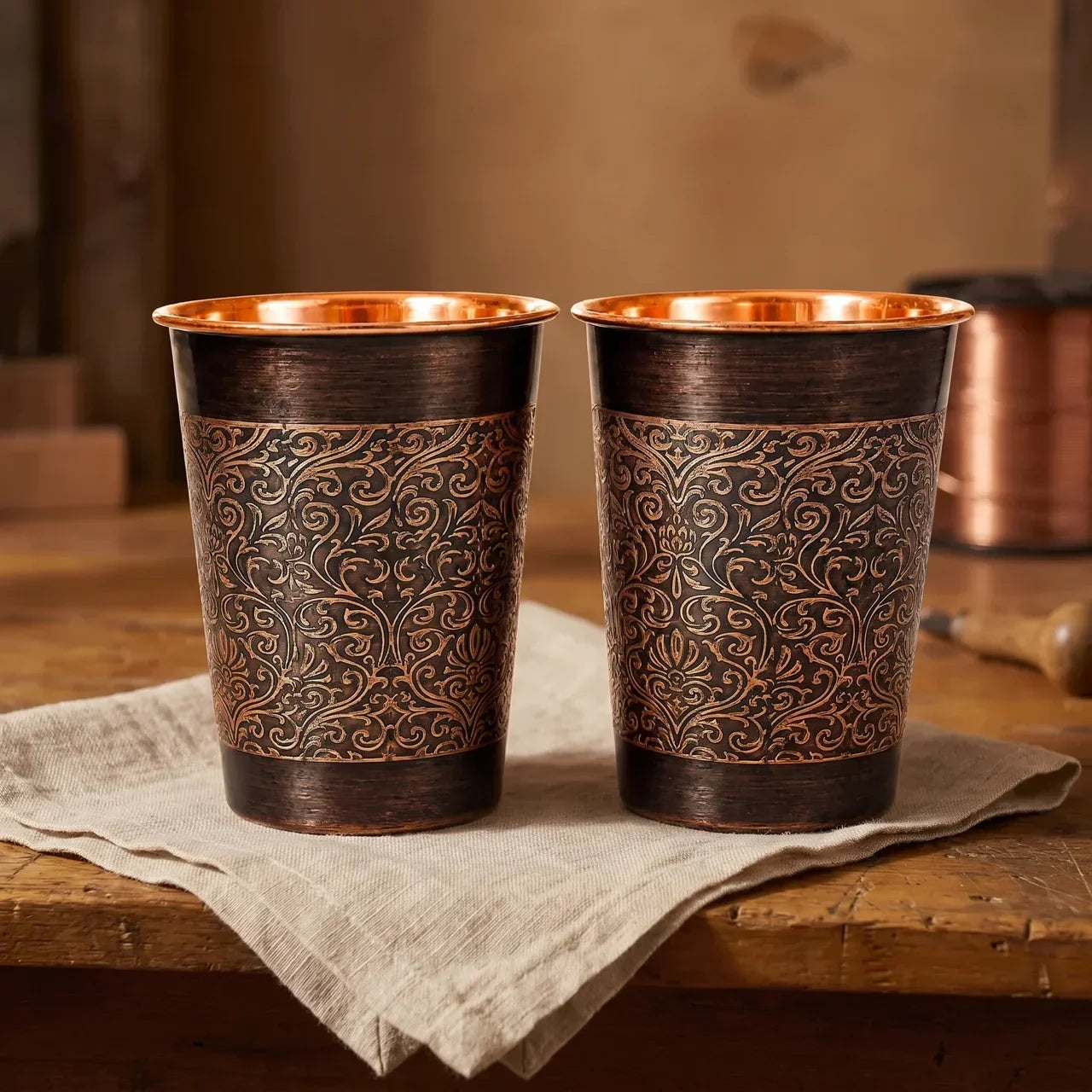 Copper mug set of 2 with ornate floral scroll pattern, dark bronze outside and copper rim