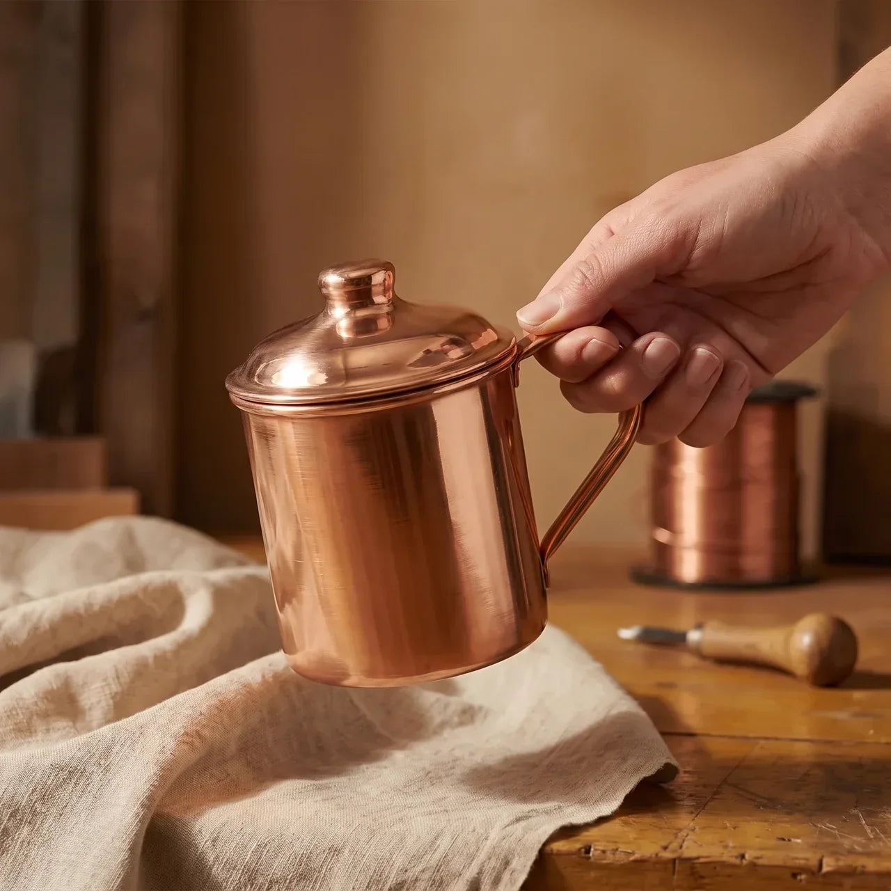 Hand-held hand-beaten copper jug with domed lid and side handle, polished finish